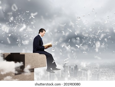 Businessman With Book Sitting On Top Of Building