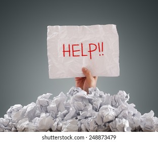 Businessman buried under crumpled pile of papers with a help sign - Powered by Shutterstock