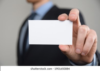 Businessman ,Business Man's Hand Hold Showing Business Card - Close Up Shot On Grey Background. Show A Blank Piece Of Paper. Paper Visit Card.