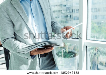 businessman in a business suit reads a magazine near the window with a plant