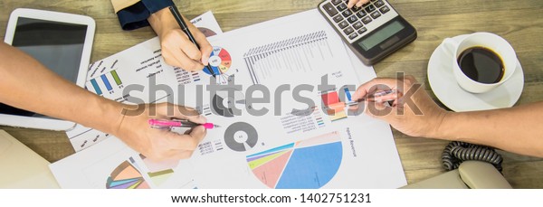 Businessman and\
Business women team analyze documents presentation shareholders\
meeting,charts and marketing plan graphs, on office\'s wooden\
table,banner web horizontal for\
header