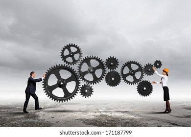 Businessman And Businesswoman With Cog Wheel Elements. Organization Concept