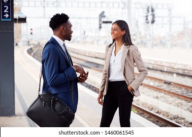 Businessman And Businesswoman Commuting To Work Talking On Railway Platform Waiting For Train