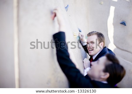 businessman and businesswoman competing by climbing on wall