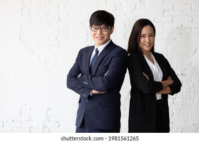 businessman and businesswoman in formal suit, standing back to back together in office
