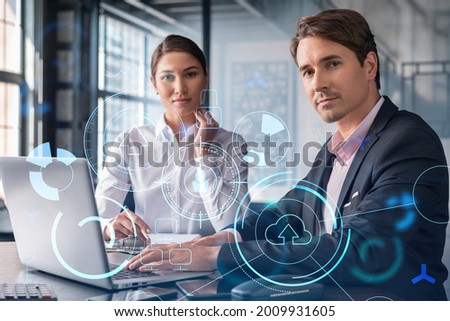Businessman and businesswoman in formal wear working together to optimize business process by applying new technologies. Hi tech holograms over modern office background with panoramic windows