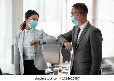 Businessman and businesswoman with medical mask in office. Greetings in Covid-19 time.