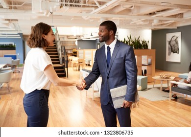 Businessman And Businesswoman Meeting And Shaking Hands In Modern Open Plan Office
