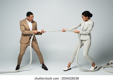 Businessman And Businesswoman Pulling Rope On Grey, Gender Equality Concept