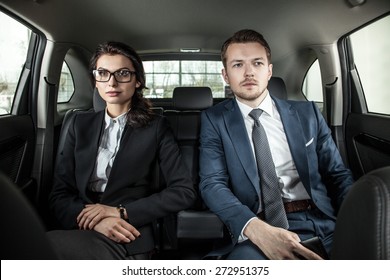 Businessman And Businesswoman Sitting In A Limousine. Young Businesswoman And Businessman In Back Seat Of Car