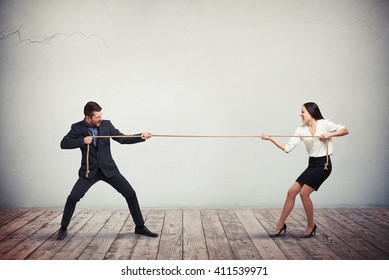 Businessman and businesswoman tug of war contest of strength conflict concept