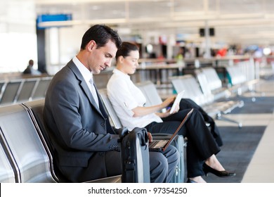 businessman and businesswoman using laptop and tablet computer at airport