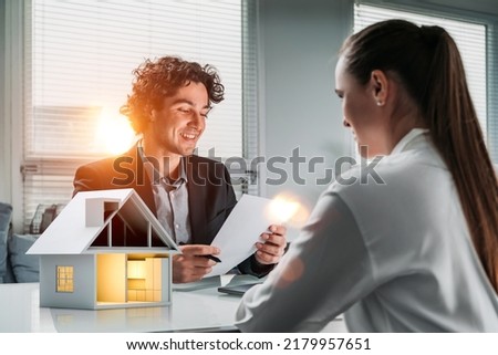 Businessman and businesswoman wearing formal suit are having a conversation about real estate insurance contract. Agent and customer. Office in background. Concept of financial protection, indemnity
