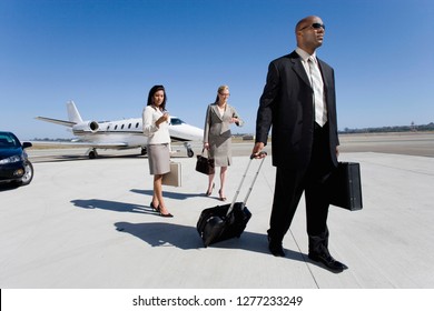 Businessman and businesswomen on runway at airport by executive jet - Powered by Shutterstock