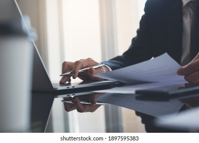Businessman busy  working on laptop computer with mobile smart phone on table at modern office. Business man reviewing business document. consultant lawyer concept