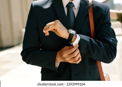 Businessman buttoning his shirt shelves walking outdoors. Close up of business professional buttoning up his shirt sleeves. - Powered by Shutterstock