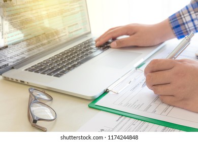 Businessman calculate bills, his workplace for Individual income tax return form with paper and laptop at tax office. - Shutterstock ID 1174244848
