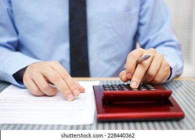 Businessman calculating  and checking articles of agreement