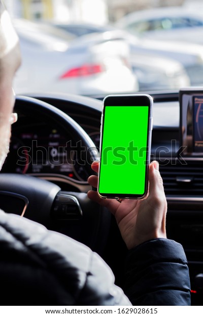 businessman in car holds\
smartphone in hands