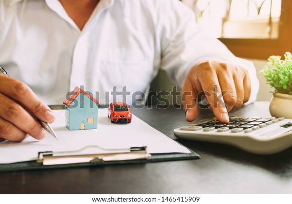 Businessman with car and home insurance\
contract and\
calculator.