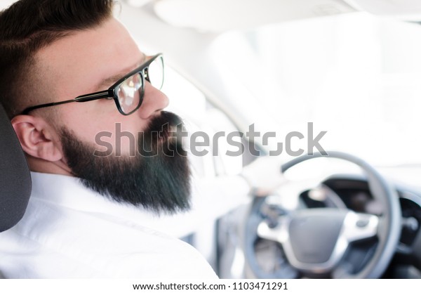 Businessman in car. Rear view of young\
handsome man looking on the right while driving a\
car