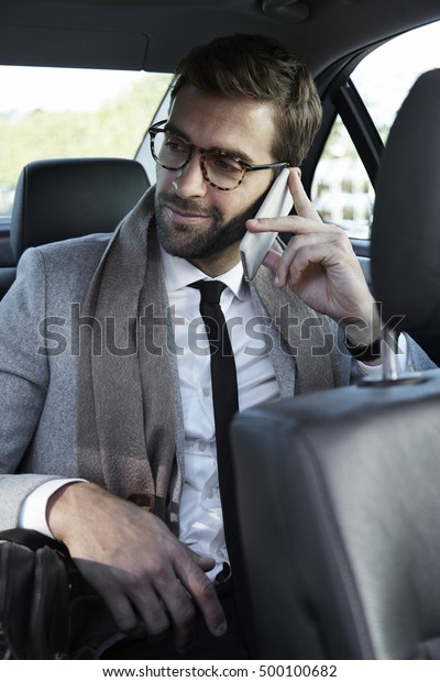 Businessman in car\
taking call on\
smartphone