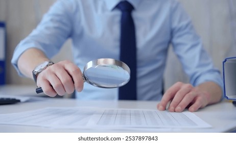 Businessman is carefully examining financial documents with a magnifying glass, highlighting the importance of thorough analysis in business. Audit and taxes