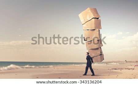 Businessman carrying big stack of carton boxes