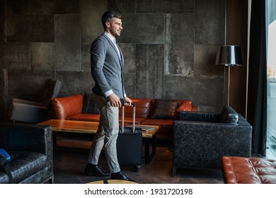 A Businessman Carrying His Luggage In The Lobby Of A Modern Hotel. He Is On A Business Trip And Is Formally Dressed And Is Just Getting Ready To Go To A Business Meeting. Travel, Luxury