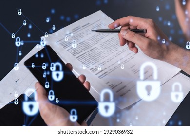 A businessman in casual wear signing the contract to prevent probability of risks in cyber security. Checking the phone. Padlock Hologram icons over the working desk. - Shutterstock ID 1929036932