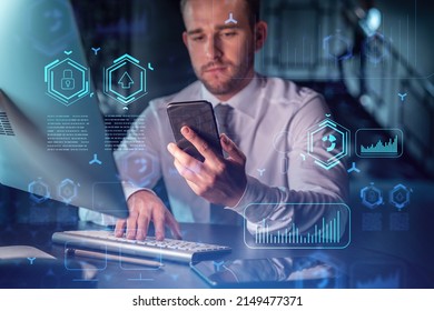 Businessman in casual wear using smart phone to optimize development by implying new technologies in business process. Interconnections and hi tech hologram over modern office background at night time