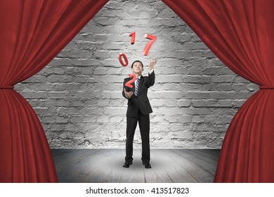 Businessman catching throwing 2017 red words on red curtain stage with spotlight, on old brick wall background. - Powered by Shutterstock