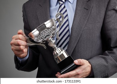 Businessman celebrating with trophy award for success in business or first place sporting championship win - Powered by Shutterstock