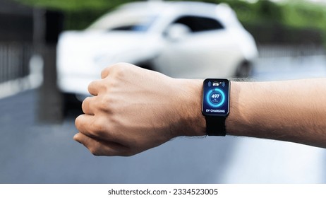 Businessman check EV car battery status on smartwatch screen while recharge from charging station city car park. Futuristic lifestyle of clean energy for EV tech adaptation. Peruse - Powered by Shutterstock