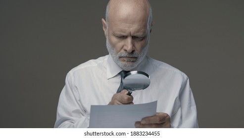 Businessman checking a document using a magnifier, contracts and agreements concept
