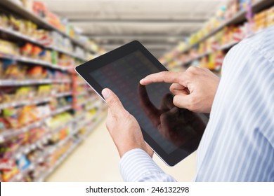 Businessman Checking Inventory In Minimart On Touchscreen Tablet