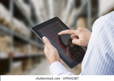 Businessman checking inventory in stock room of a manufacturing company on touchscreen tablet - Shutterstock ID 199541387