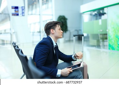 businessman checking time and using tablet at airport.