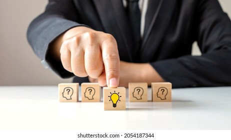 Businessman Choosing Light Bulb Icon, Full Of Ideas And Creativity On The Wooden Cube, Financial Planning Ideas To Achieve Goals.