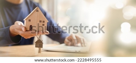 Businessman choosing mini wood house model from model and Planning to buy property. Choose what's the best. A symbol for construction ,ecology, loan concepts.