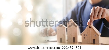Businessman choosing mini wood house model from model and Planning to buy property. Choose what's the best. A symbol for construction ,ecology, loan concepts.