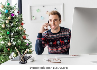 Businessman In Christmas Sweater Talking On Smartphone In Modern Office   