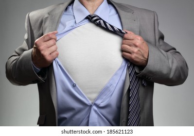 Businessman in classic superman pose tearing his shirt open to reveal t shirt with blank chest for message