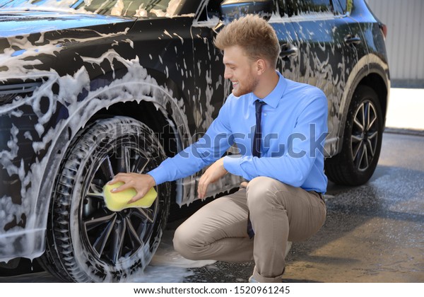 Businessman cleaning auto with sponge at\
self-service car\
wash