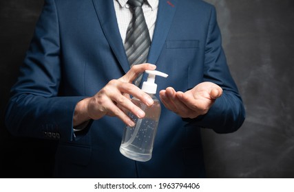 businessman cleans his hands with antiseptic on black background - Powered by Shutterstock