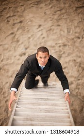 Businessman Climbing Ladder On Beach