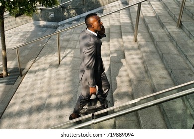 A businessman climbs the stairs to go to the office at work while talking on the phone and smiles satisfied with the phone call with the finance client. Concept of: finance, businessman, technology - Powered by Shutterstock