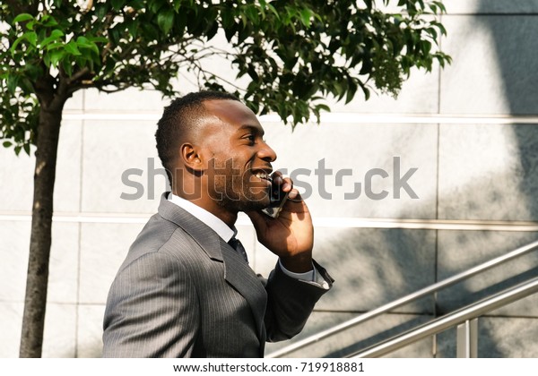 A businessman climbs the stairs to go to the\
office at work while talking on the phone and smiles satisfied with\
the phone call with the finance client. Concept of: finance,\
businessman, technology