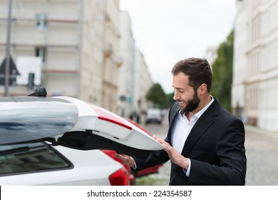 Businessman Closing The Boot Of His Car As He Retrieves His Belongings Before Leaving It In The Parking Lot