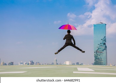 Businessman with colorful of umbrella jumping from rooftop ,city background ,successful concept - Powered by Shutterstock